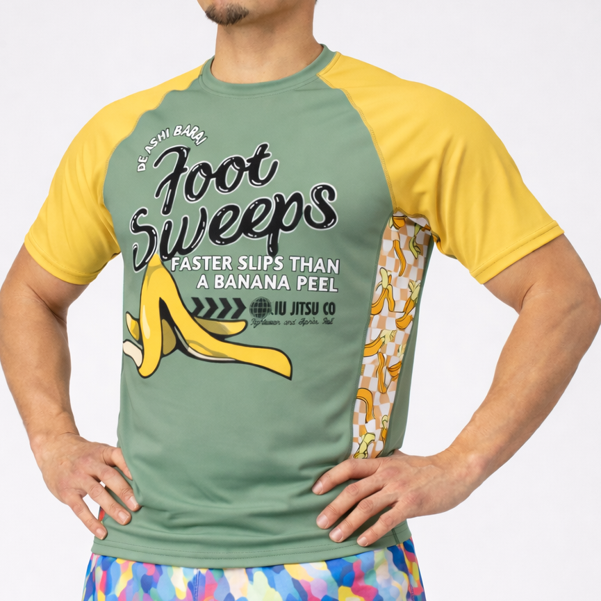 Man wearing a green and yellow shirt with a graphic design and colorful shorts on a white background
